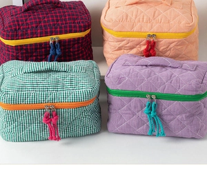 Detail of four quilted plaid makeup bags with vibrant zippers and woven pullers