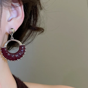 Detailed view of silver dangle earring with burgundy textured wrap on model ear