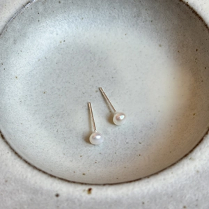 Gros plan de boucles d'oreilles en perles d'eau douce sur un plat en céramique blanc
