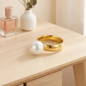 Detail view of a vintage 18k gold plated wide band ring with a large white pearl on wood