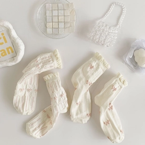Detail of white ruffled socks with pink bow patterns and vertical ribbed texture