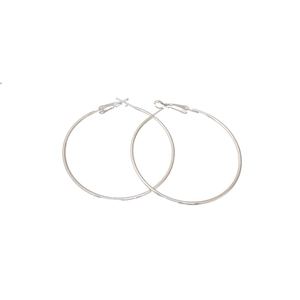 Créoles classiques en métal argenté avec un design rond minimaliste sur fond blanc