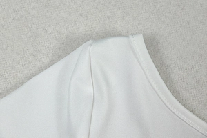 Detailed macro view of white crew neck stitching and fine mesh texture on dress shoulder