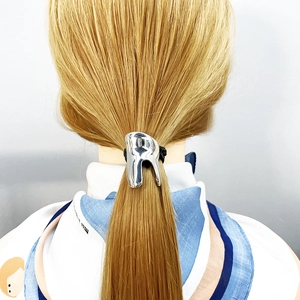Detail of a minimalist silver U-shaped alloy ponytail cuff on hair with a sleek metallic finish