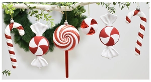 Close-up of red and white candy cane and lollipop ornaments with glitter on a white tree