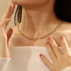 Close-up of elegant gold beaded necklace worn by a model in soft lighting