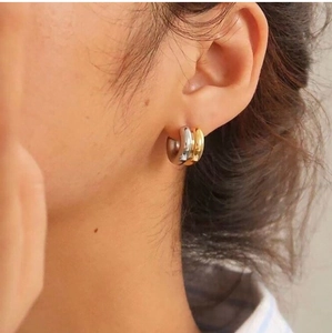 Close-up of model wearing two-tone gold and silver C-shaped double layered hoop earrings