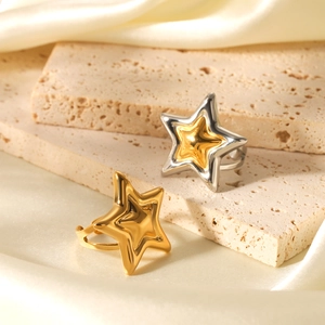 Close-up of star-shaped gold and silver stainless steel rings on a silk background