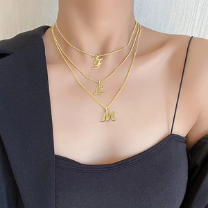 Close-up of a three-layer gold necklace featuring F, L, and M letter pendants on a model