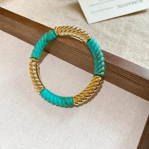 Detail of twisted gold metal and turquoise resin links on a stylish geometric bracelet