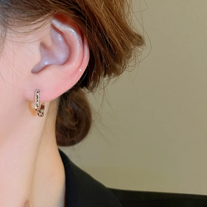 Close-up of minimalist silver hollow flower earrings worn on the ear for a stylish look