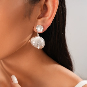 Detailed view of silver metallic shell earrings with pearl inlay worn by a model