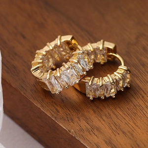 Elegant gold earrings with double rows of rectangular cubic zirconia on a wooden background