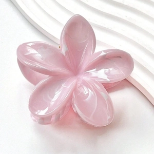 Gros plan sur la pince à cheveux fleur rose avec texture marbrée et ressort doré
