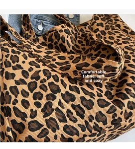 Close-up of leopard print canvas tote bag texture with matching wide shoulder strap