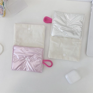 Detail of silver quilted pouch with bow pattern, snap button, and lifestyle props
