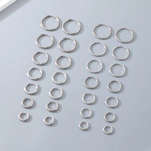 Polished silver stainless steel hoop earrings set in multiple sizes on grey background