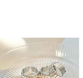 Close-up of textured gold and silver titanium rings displayed on a clear glass tray