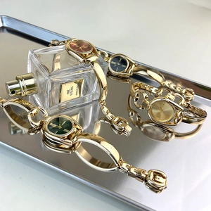 Vintage gold link bracelet watch for women with colorful dials on a metal tray