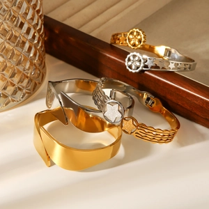 Artistic layout of gold and silver stainless steel star bangles on geometric glass display