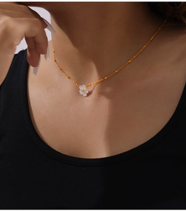 Close-up of elegant 18K gold-plated necklace with a white shell flower pendant on neck