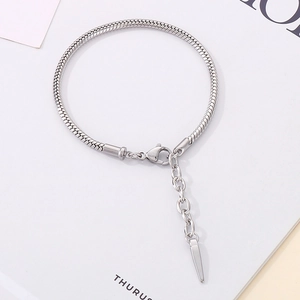 Detailed macro of silver snake chain bracelet with lobster clasp and spike charm