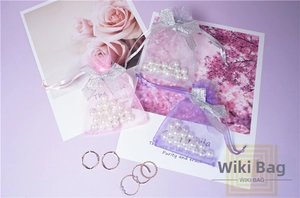 Close-up of sheer organza drawstring bags with silver bow and decorative white pearls