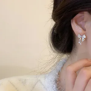Détail de boucles d'oreilles nœud en argent avec zircon et pendentifs en forme d'étoile