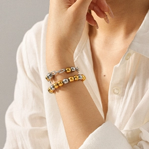 Détail de bracelets en acier inoxydable bicolore or et argent portés au poignet d'une femme
