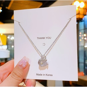 Close-up of a silver swan pendant necklace with white crystals on a gift card