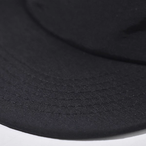 Gros plan sur la visière d'une casquette noire avec quatre rangées de coutures précises