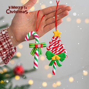 Christmas tree and candy cane clay ornaments held by hand with warm festive background