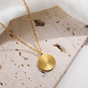 Close-up of 18K gold-plated round pendant with sunburst texture on white stone