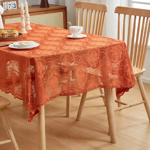 Close-up of vintage warm orange lace tablecloth with floral jacquard and scalloped edges