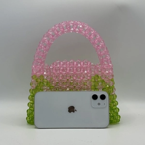 Pink and green gradient beaded bag next to a smartphone for size comparison