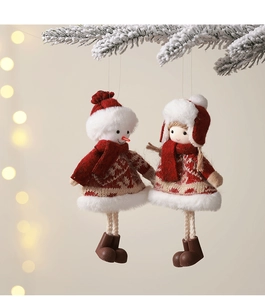 Detail of plush Christmas snowman and girl dolls hanging on snow-covered pine branches