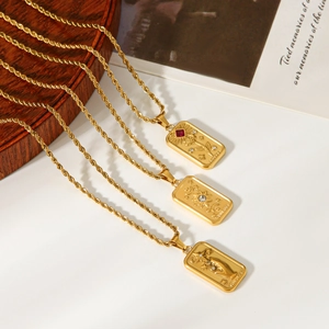 Three gold tarot pendants with rose and sun moon charms on rope chains over a wooden tray