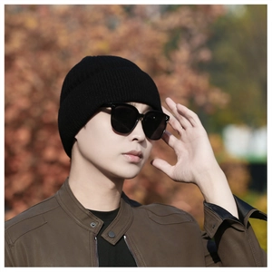Close-up of black ribbed knit beanie worn by model in a stylish outdoor winter setting