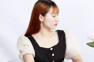 Silver round earrings with playful doll silhouette cutout on a model with pink roses