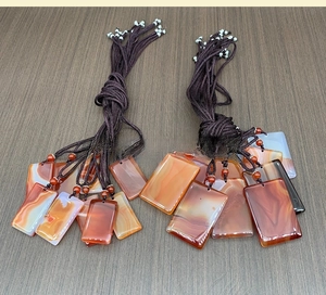 Macro view of rectangular chalcedony pendants with natural red and orange agate stripes