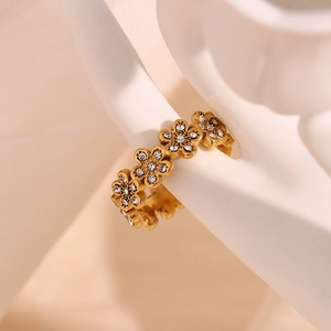 Détail d'une bague marguerite dorée sertie de cristaux blancs sur un modèle d'art