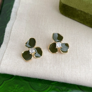 Detailed close-up of dark green flower stud earrings with a square zircon center