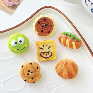 Close-up of 6 cute miniature food brooches including burger and croissants on a ceramic plate