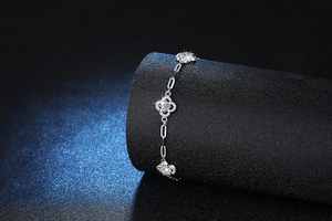 Macro shot of silver S925 clover bracelet with moissanite diamonds on dark texture
