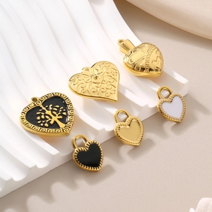 Close-up of assorted golden heart pendants with enamel and cutout details on white stand