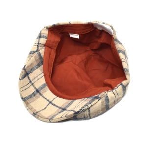 Flat lay of vintage plaid beret hat with beige check pattern and orange fabric lining
