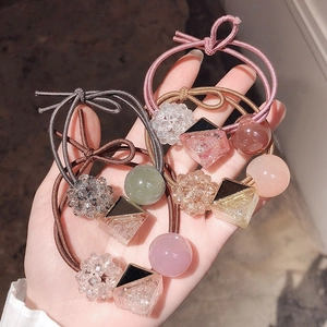 Detailed view of colorful elastic hair ties with assorted crystal and resin beads in hand