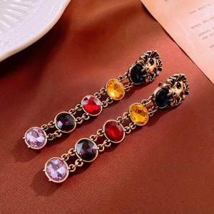 Detail view of vintage bronze lion head earrings with multi-colored gemstone fringe