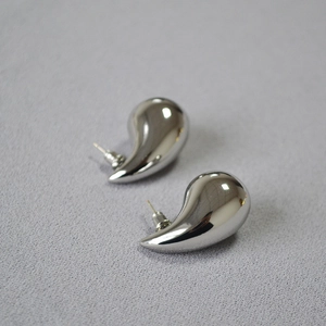 Macro shot of silver teardrop earrings with a high-shine mirror polished metal finish