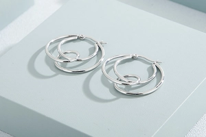 Detailed view of silver multi-layer crossover hoop earrings on geometric cubes